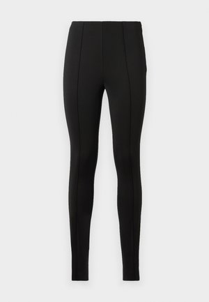 Leggings neri realizzati in un tessuto elastico, con una texture liscia, altezza vita alta e dettagli con cuciture verticali lungo le gambe.