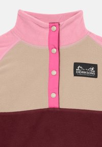 Pullover in pile di colori rosa, beige e bordeaux. Presenta un colletto alto, bottoni a pressione e un'etichetta con il logo sulla parte anteriore.
