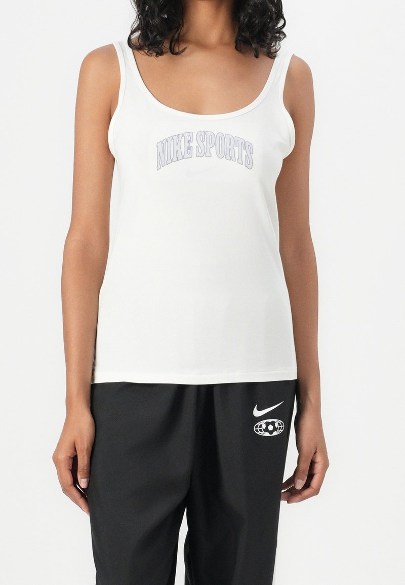 Bílý top na ramínka s nápisem "NIKE SPORTS" napsaným šedě, úzké ramínka a hladká, lehká látka. V kombinaci s černými kalhotami.