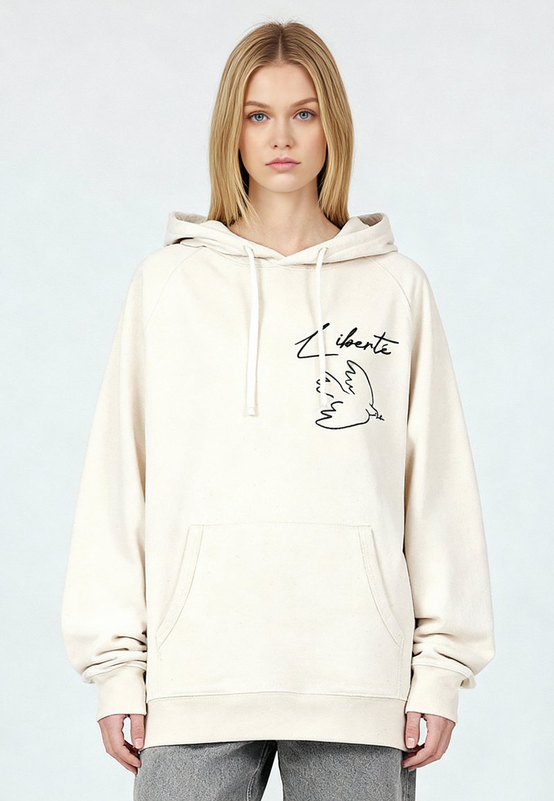 Felpa con cappuccio color crema con tasca frontale, cappuccio con coulisse e grafica nera stampata di una colomba con la parola "Liberté." Morbida, vestibilità comoda.