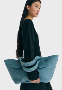 Blaue Wildleder-Handtasche mit weitem Öffnung und Obergriffen. Verfügt über ein flaches, strukturiertes Design und eine glatte Textur; keine sichtbaren Verzierungen.