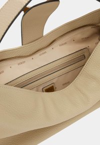 Borsa a mano in pelle beige con superficie texture, interno foderato con stampa del logo, tasca con cerniera e tracolla regolabile.