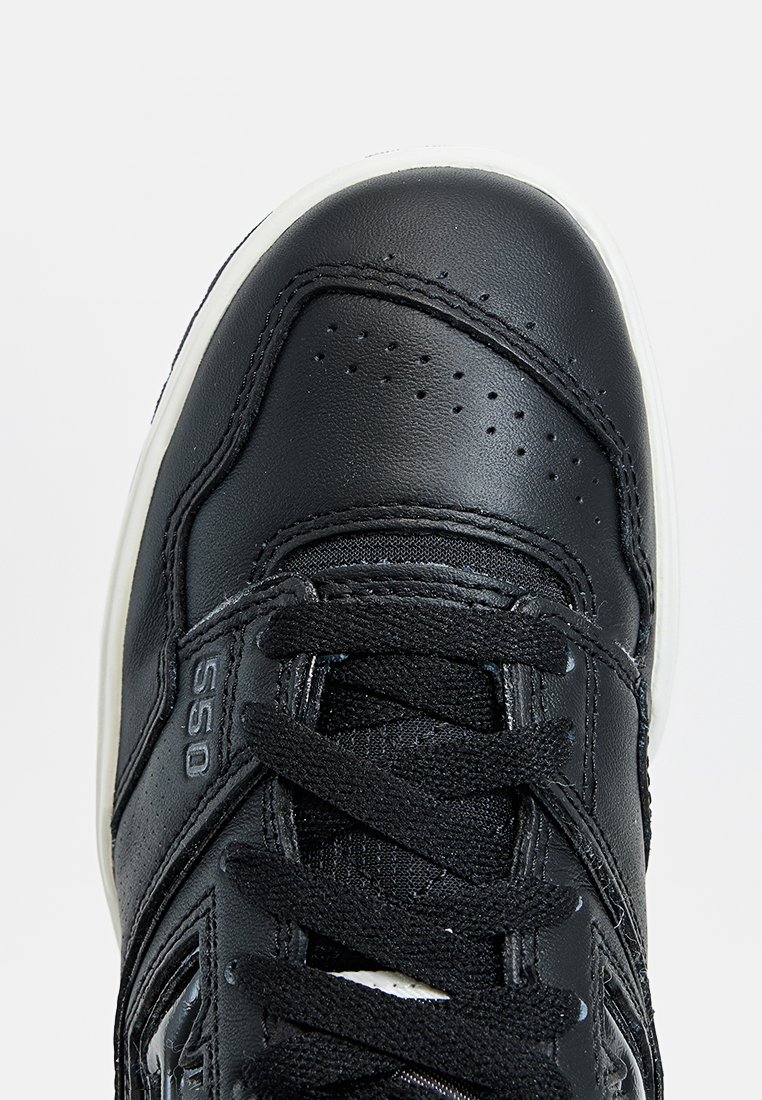 Schwarze Sneaker mit Obermaterial aus Leder, strukturiertem Oberfläche, gepolstertem Schaft und flachen Schnürsenkeln. Verfügt über Perforationen und eine weiße Gummisohle.