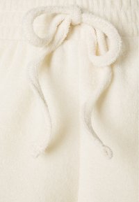 Krämfärgade handdukstygshorts med en mjuk textur, med en dragsko vid midjan. Enkelt design, inga synliga mönster.