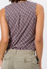 Top sans manches à motifs présentant un design hexagonal en rouge, marine et blanc ; tissu lisse avec un léger éclat et détail de pli au dos.