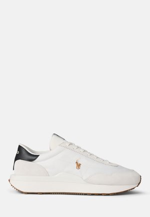 White low-top sneaker with beige suede accents, black heel tab, brown polo player logo, and white rubber sole with textured brown outsole.