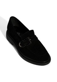 Zwarte suède loafers met een ronde neus, een gestructureerde bovenkant en een decoratieve zilveren gesp. Voorzien van een dikke, gestructureerde rubberen zool voor stabiliteit.