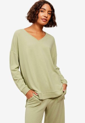 Hellgrüner, oversized V-Ausschnitt-Pullover mit gerippten Bündchen und Saum. Weicher Stoff mit dezentem Muster. Kombiniert mit passenden Jogginghosen mit Taschen.