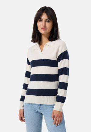 Marineblauwe met crèmekleurige gestreepte trui in zachte brei met een V-hals en korte kraag, voorzien van geribbelde manchetten en zoom. Gecombineerd met lichtblauwe jeans.