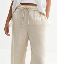 Pantalons en lin beige, à jambes larges, avec une taille à cordon et une texture subtile. Les poches sont visibles le long des coutures latérales.