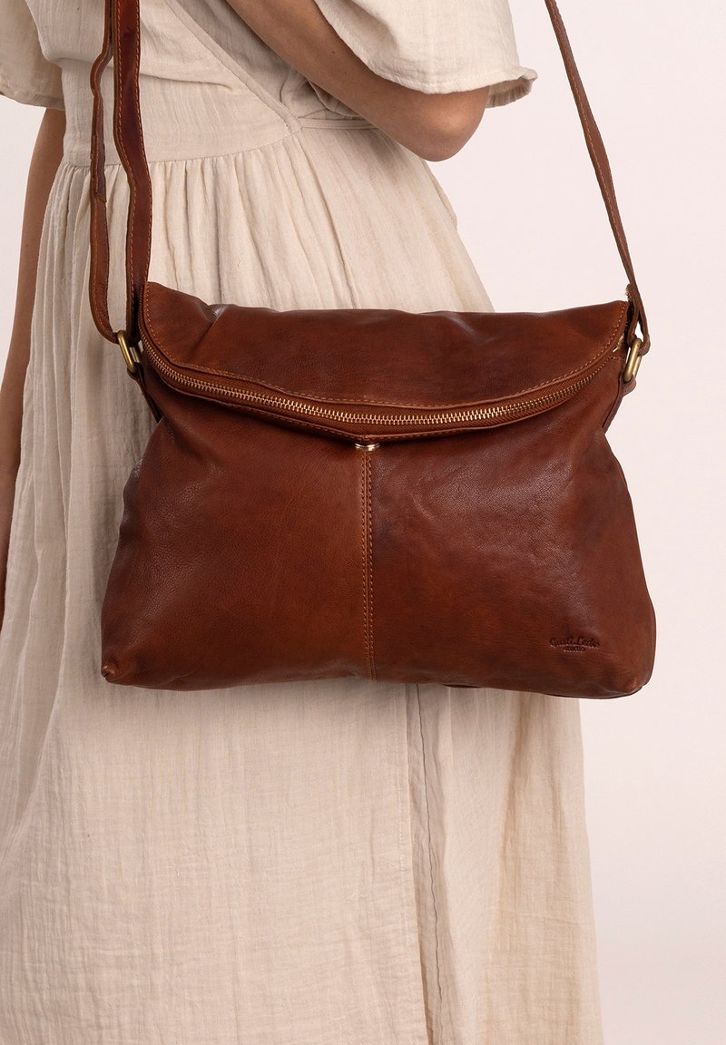 Brown leather shoulder bag with a zip closure and fold-over flap. It features a smooth texture and a gold-tone hardware accent.