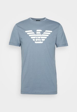 Lichtblauw katoenen T-shirt met korte mouwen, met wit gestileerd adelaarlogo en de letters "GA" in het midden op de borst.