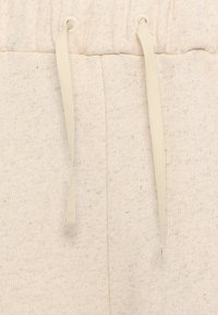 Lys beige joggebukser med strukturert stoff, elastisk midje og matchende snorer. Ideelle for hverdagsbruk og komfort.