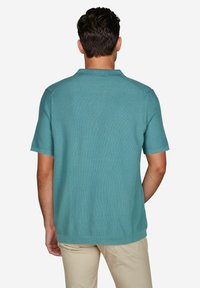 Korte mouwen polo-shirt in textuur teal stof, met een klassieke kraag en een relaxte pasvorm, met subtiele ribbels langs de schoudernaden.