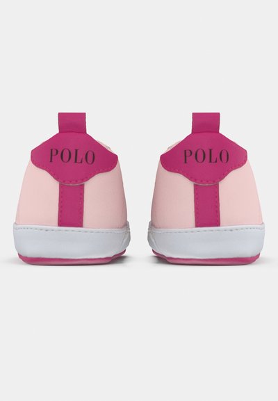 Różowe i jasnoróżowe buty dziecięce z różowym językiem, białą podeszwą i czarnym logo "POLO" z tyłu. Gładka tekstura, zaokrąglony kształt.