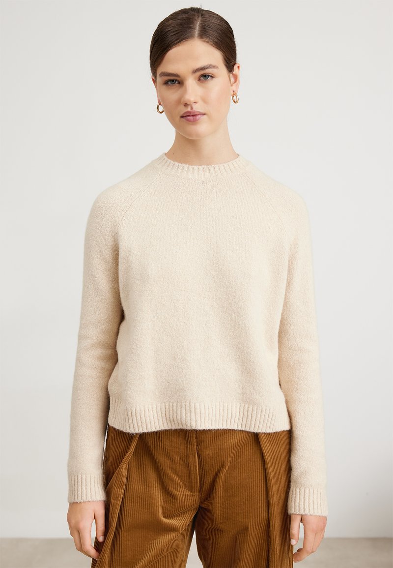 Beige gestrickter Pullover mit runden Ausschnitt, gerippten Bündchen und cropped Saum. Weiche Textur mit leicht flauschigem Finish.
