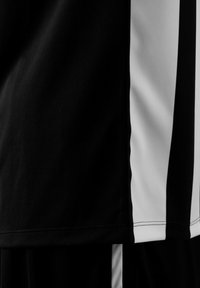 Maillot de sport noir et blanc avec des rayures verticales. Fabriqué en tissu léger et respirant avec une texture lisse.