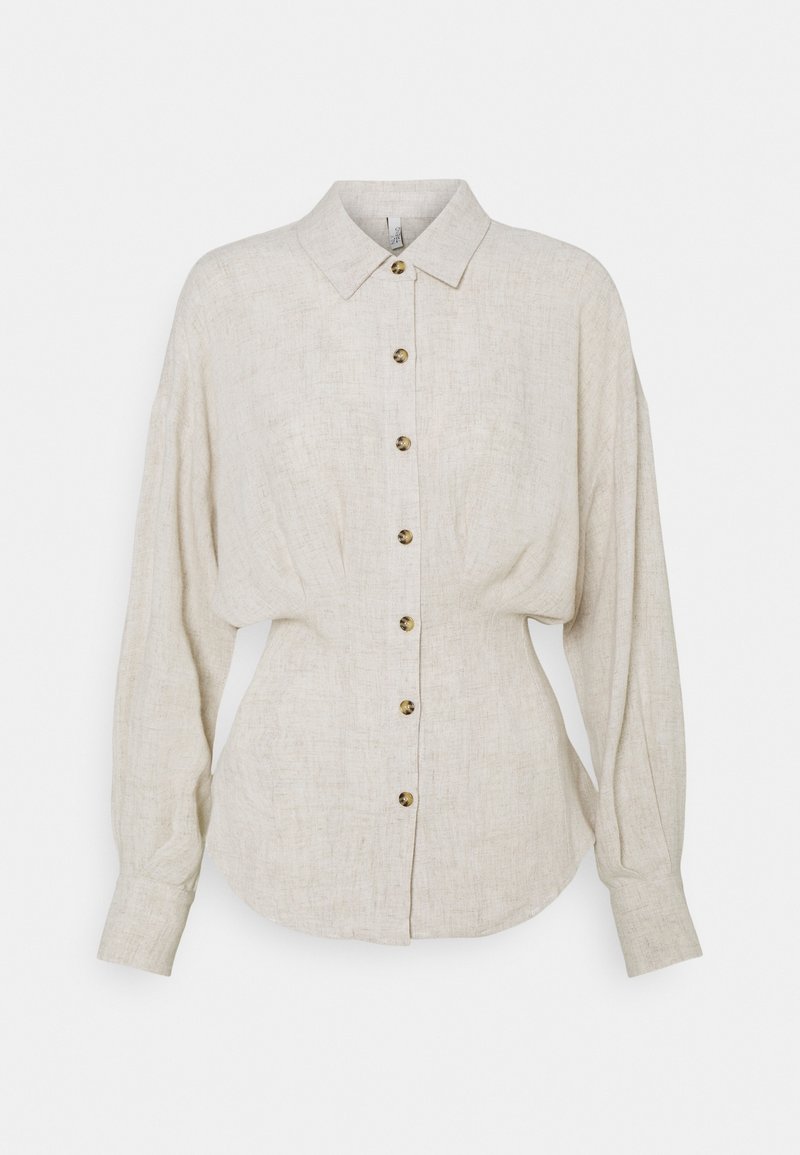 Chemise en lin beige clair à boutons, avec un col pointu, des manches longues et un ourlet arrondi ; accentuée par des boutons marron.