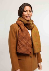 Écharpe marron et jaune à motifs, avec une surface rainurée texturée et un design en nid d'abeille, drapée autour du cou d'un mannequin.