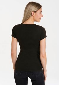 Black fitted t-shirt with short sleeves, round neck, and a smooth texture. Cut close to the body, with no visible patterns or graphics.