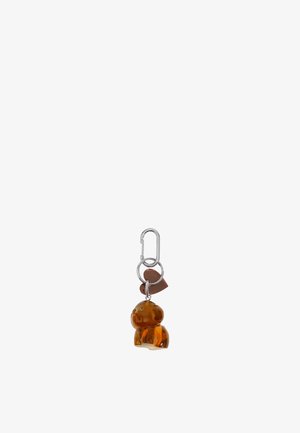 Llavero con colgante en forma de perro color ámbar, con mosquetón plateado y un pequeño corazón marrón adjunto.