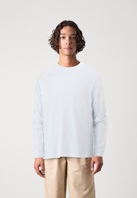 Light blue long-sleeve t-shirt in soft cotton fabric with a round neckline. The fit is relaxed with ribbed cuffs and a straight hem.