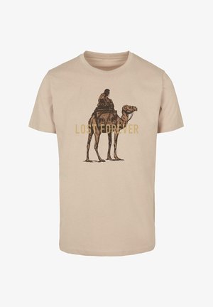 Beežist puuvillast T-särk, mille esiküljel on graafiline kujutis inimesest, kes sõidab kaameliga ja kannab boomboksi, ning tekst "KAOTATUD IGAVESTI" kuldsetes tähtedes.