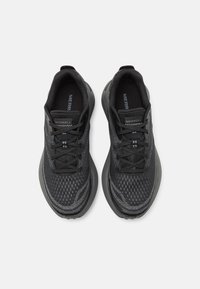 Zapatillas deportivas negras con una parte superior de malla transpirable, diseño texturizado, puntera redonda, cordones y una suela de goma para tracción.