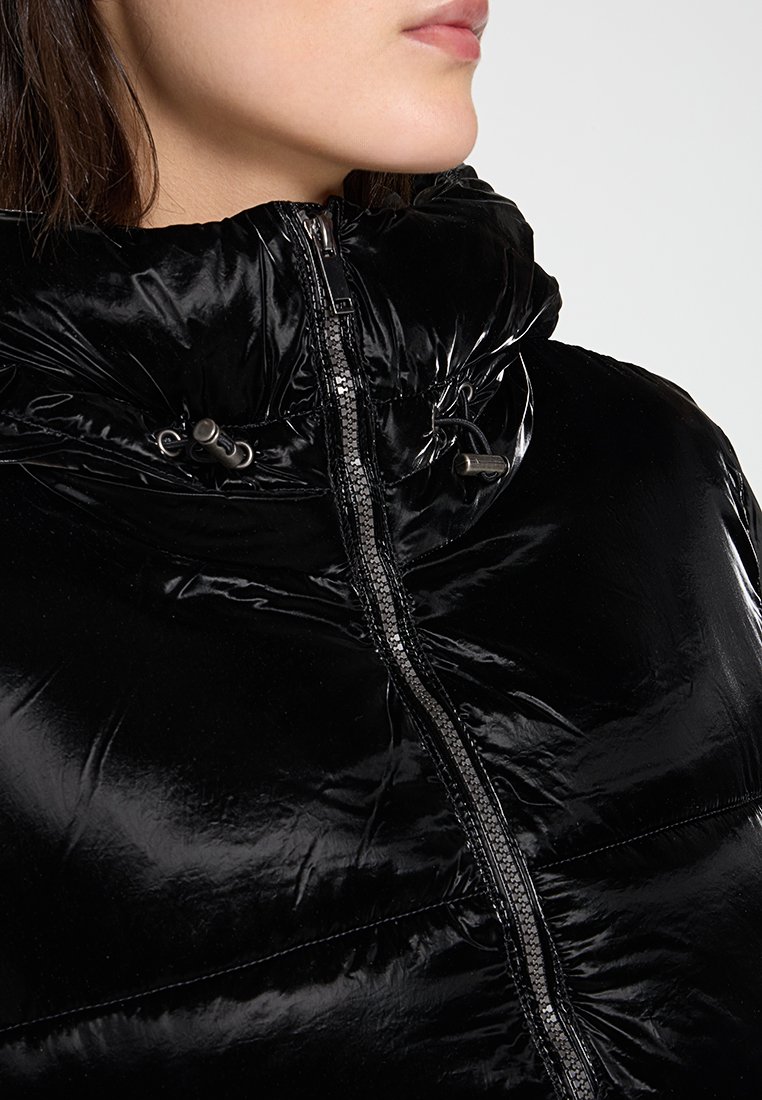 Veste rembourrée noire et brillante avec un col haut, une fermeture éclair et des détails à cordon au niveau de la capuche, présentant une texture matelassée.