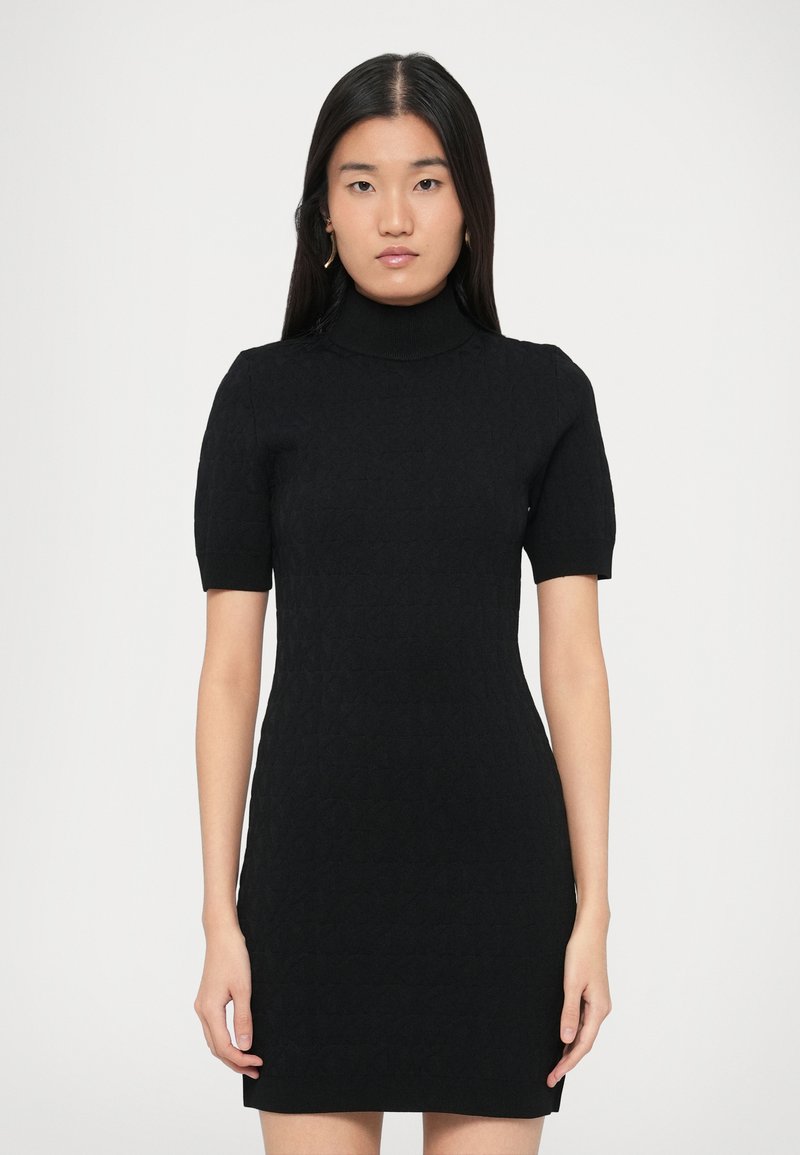 Crna pletena haljina s visokim ovratnikom, kratkim rukavima i pripijenim krojem. Ima teksturirani uzorak na cijelom tkanju.