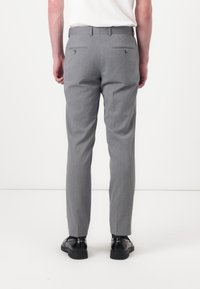 Pantalon gris au fini texturé, avec une coupe slim, des poches arrière avec boutons et un design à jambes droites.