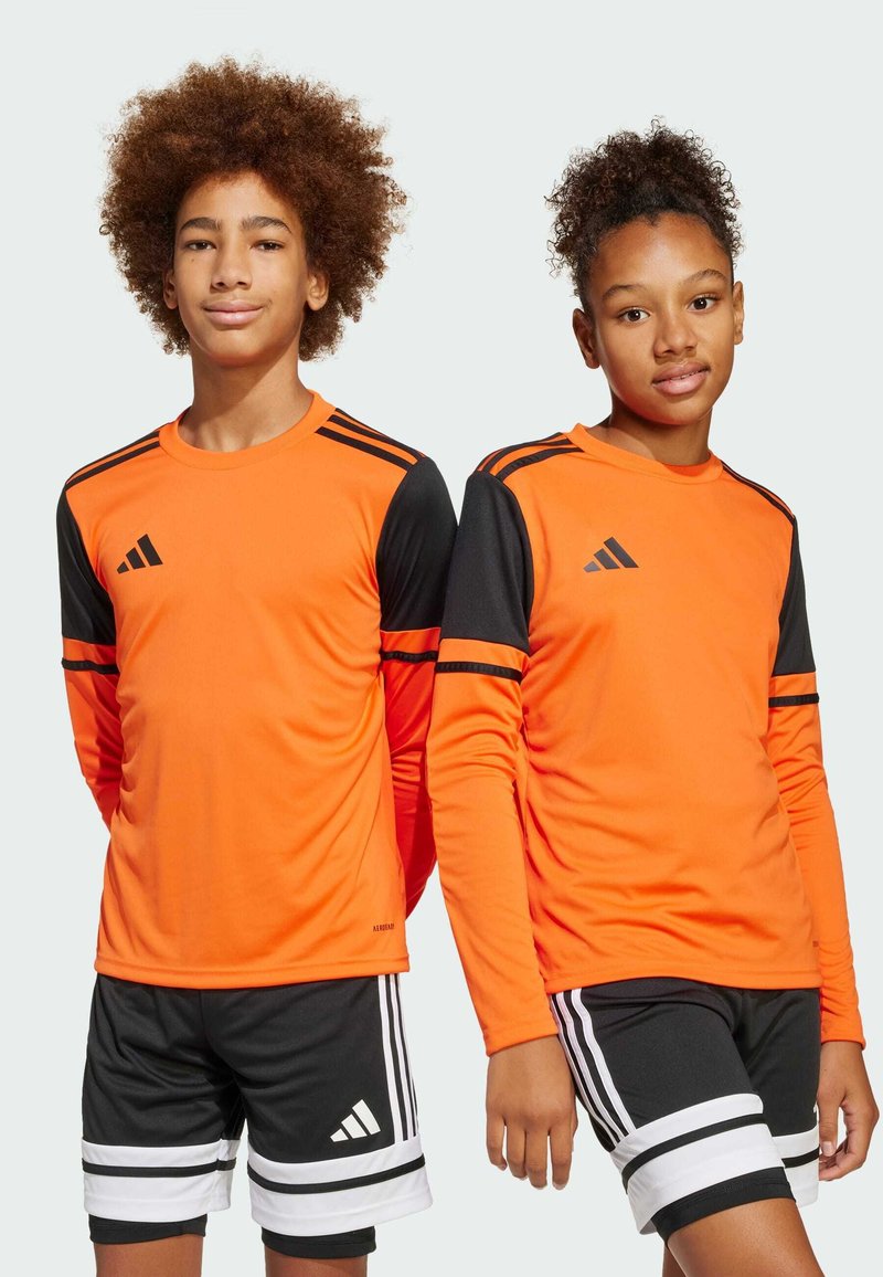 Langdrogende sportshirts met lange mouwen in fel oranje met zwarte mouwen en drie strepen. Gecombineerd met zwarte shorts met witte strepen.