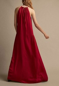 Robe longue rouge fluide avec un col licou froncé, un dos ouvert et de subtils plis à l'ourlet. Le tissu doux offre une texture lisse.