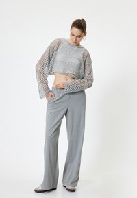 Grijze cropped mesh top met een loose fit en lange mouwen, gecombineerd met grijze pinstriped wijde broek, met een gladde textuur.