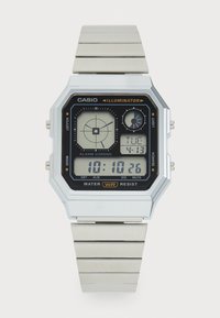 Montre numérique rectangulaire argentée avec un cadran noir affichant plusieurs écrans, un bracelet en acier inoxydable et diverses fonctions de boutons sur les côtés.