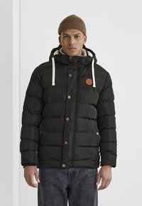 Veste doudoune noire avec capuche, cordons de serrage contrastants, patch logo sur la poitrine et fermetures à bouton. Design texturé et matelassé avec poches latérales.