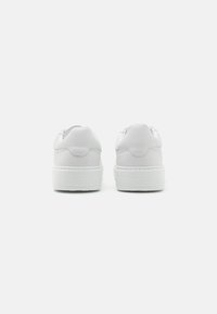 Witte leren sneakers met een gladde afwerking, voorzien van een gevoerde hiel en een verhoogde rubberen zool. Eenvoudig ontwerp zonder zichtbare logo's of patronen.