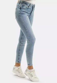 Jasnoniebieskie wąskie dżinsy wykonane z denimu, z pięcioma kieszeniami, z zapięciem na guzik i lekko wyblakłym wykończeniem. Połączone z białymi sneakersami.