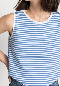 Randig ärmlös topp i vitt och ljusblått tyg, rund halsringning, mjuk textur, med en avslappnad passform och synliga sömnadsdetaljer.