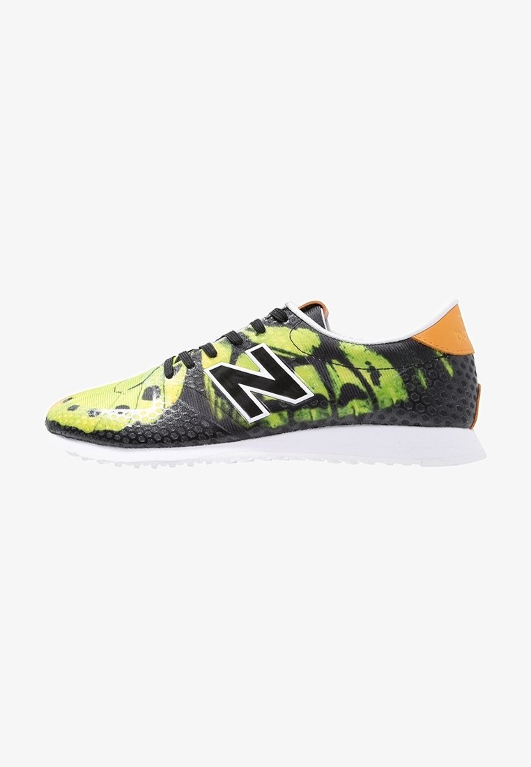 Baskets de sport noires et jaunes avec une tige texturée, arborant un grand logo "N" blanc, des lacets fins et un accent de talon orange.
