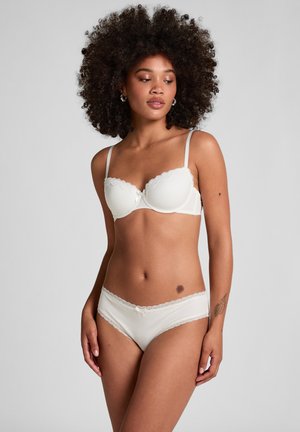 Hvid ribbet bh med bølget blondedetalje og sløyfebeslag; matchende hvidt hipster-trusser med blondedetaljer. Glat tekstur, støttende design.