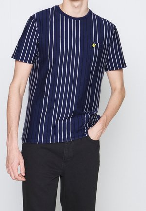 Granatowa koszulka w paski z białymi pionowymi paskami, krótkimi rękawami, okrągłym dekoltem i kieszonką na piersi z małym żółtym logo.