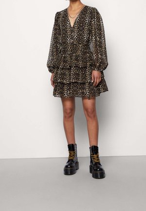 Robe courte à imprimé léopard avec manches ballon longues, volants superposés et décolleté en V profond. Assortie à des bottes à plateforme noires lacées.