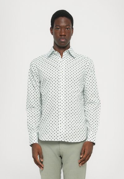 Chemise à manches longues avec boutons en tissu vert clair ornée d'un motif de petits pois noirs, dotée d'un col classique et d'une silhouette ajustée.