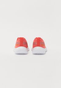 Scarpe da ginnastica rosse con tomaia in tessuto liscio, suole in gomma bianca e dettagli riflettenti argentati. Logo Reebok arancione. Design arrotondato.