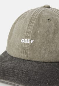 Two-tone olive green and dark gray baseball cap with white embroidered "OBEY" text on front panel.