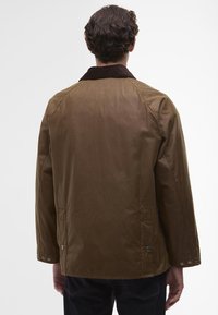 Brown coat with a corduroy collar, featuring a straight cut, snap button accents at the waist, and side pockets. Smooth texture.