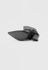 Bottines noires à bout pointu, en cuir texturé, avec des accents matériels uniques et un design de talon épais.