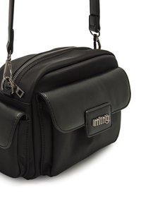 Borsa a tracolla nera in materiale sintetico con zip nella parte superiore, patta frontale magnetica e logo in metallo, con due tasche frontali e una finitura testurizzata.