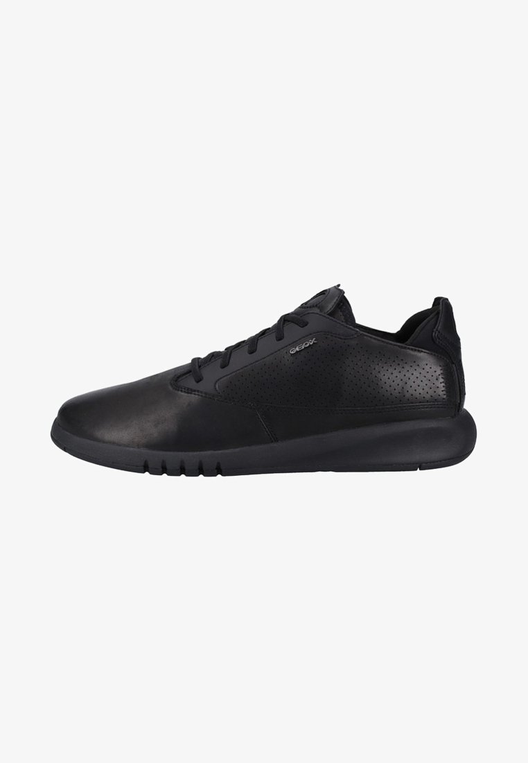Zapatillas negras con un upper de piel suave y detalles perforados, suela acolchada y un diseño elegante y minimalista.
